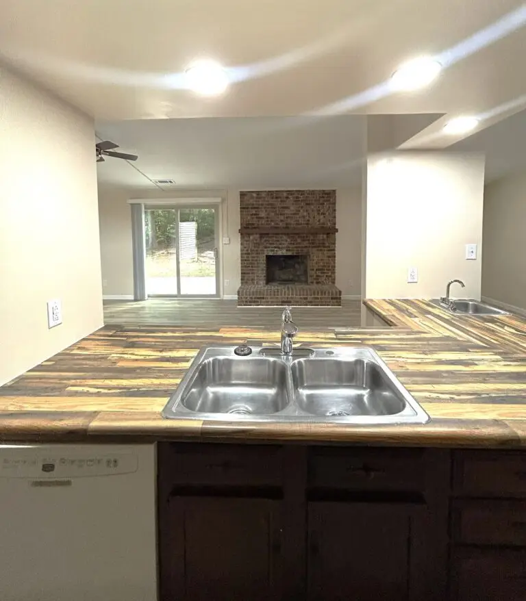 Open kitchen with peninsula counter looking through to a living room with brick fireplace in a Charlotte shared rental home