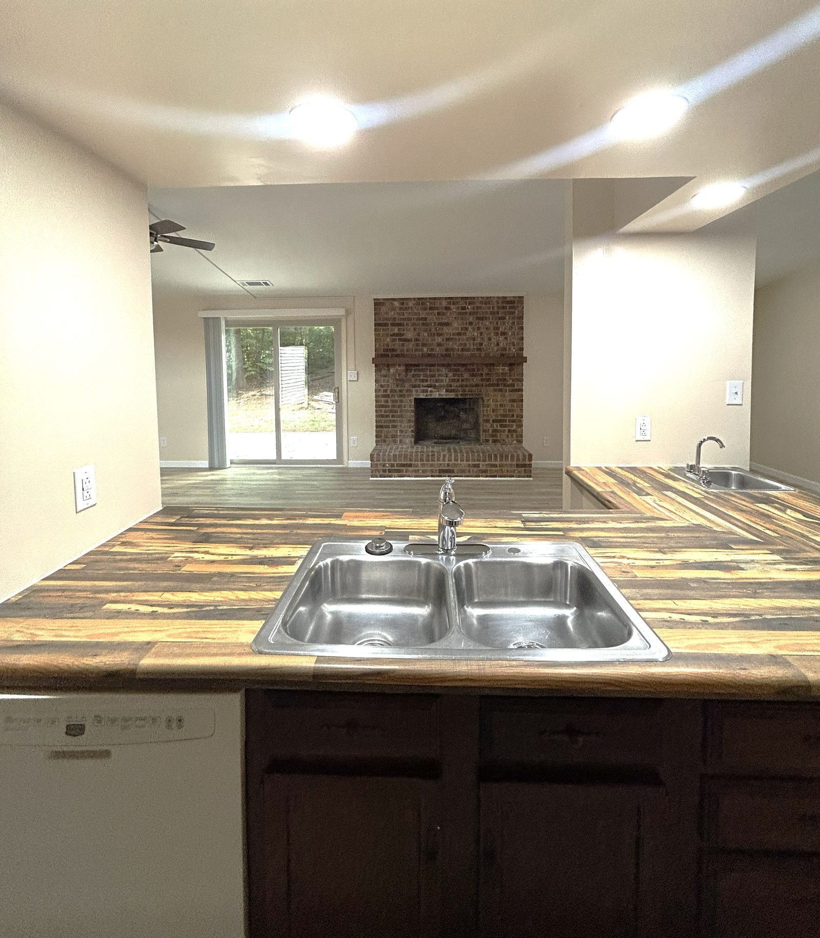 Open kitchen with peninsula counter looking through to a living room with brick fireplace in a Charlotte shared rental home